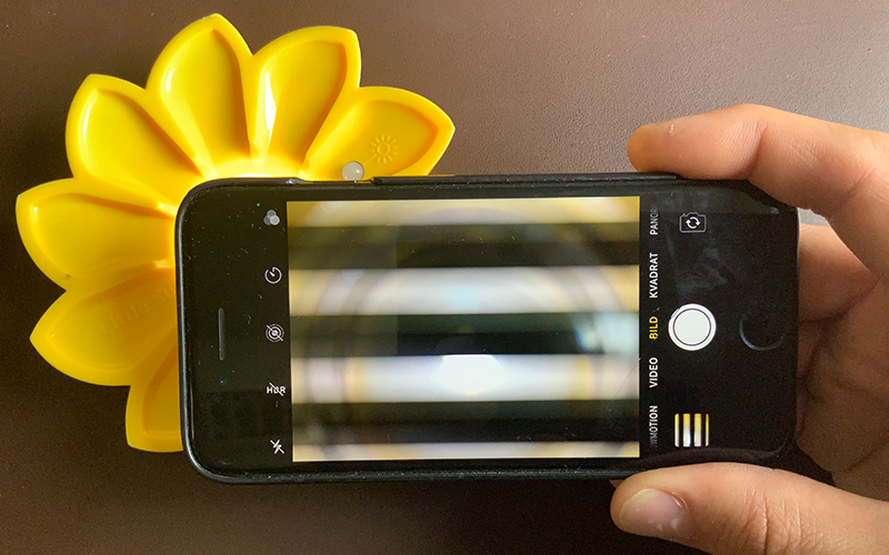 Foto av en mobiltelefon vars skärm visar en randig bild av en lampa.