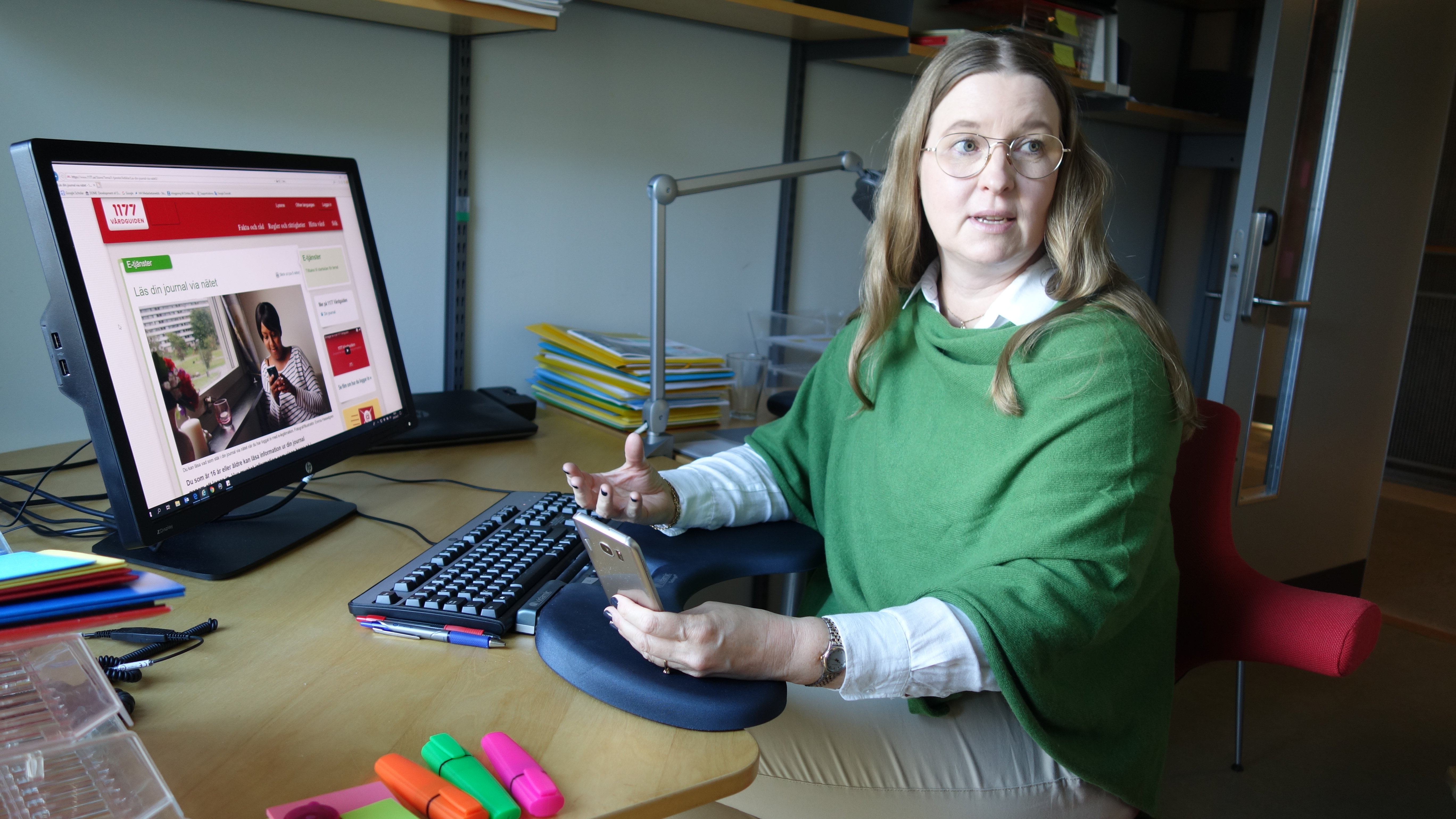 Lena Petersson sitter vid datorn med 1177 på skärmen. Foto.