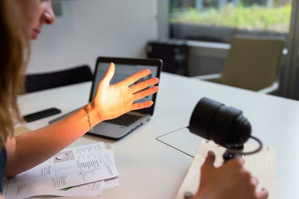 En lampa lyser upp en persons hand. Foto.