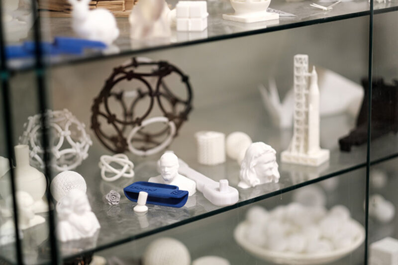 3D-printade objekt i en glashylla. Foto. 
