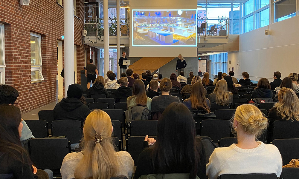 Ett stort rum med åhörare och två som presenterar på en scen.