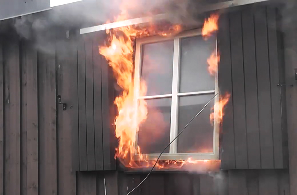 eldslågor slår ut från ett fönster. Foto. 