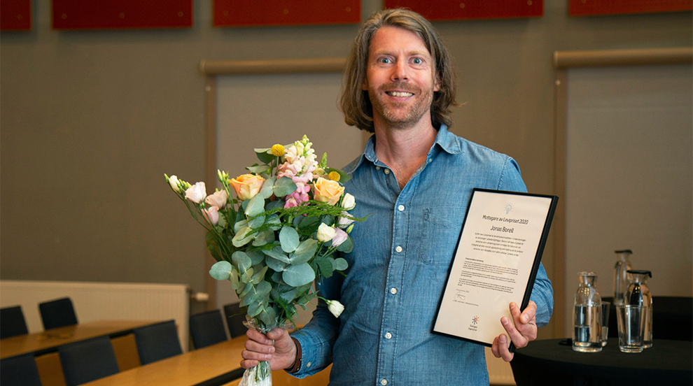 Jonas Borell tar emot diplom och blommor. Foto. 