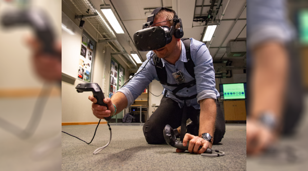 person i VR-headset kryper på golvet. Foto. 