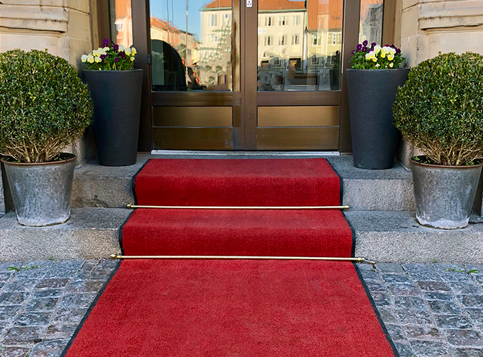 en röd matta är utrullad till en entré och slutar med två trappsteg. Foto. 