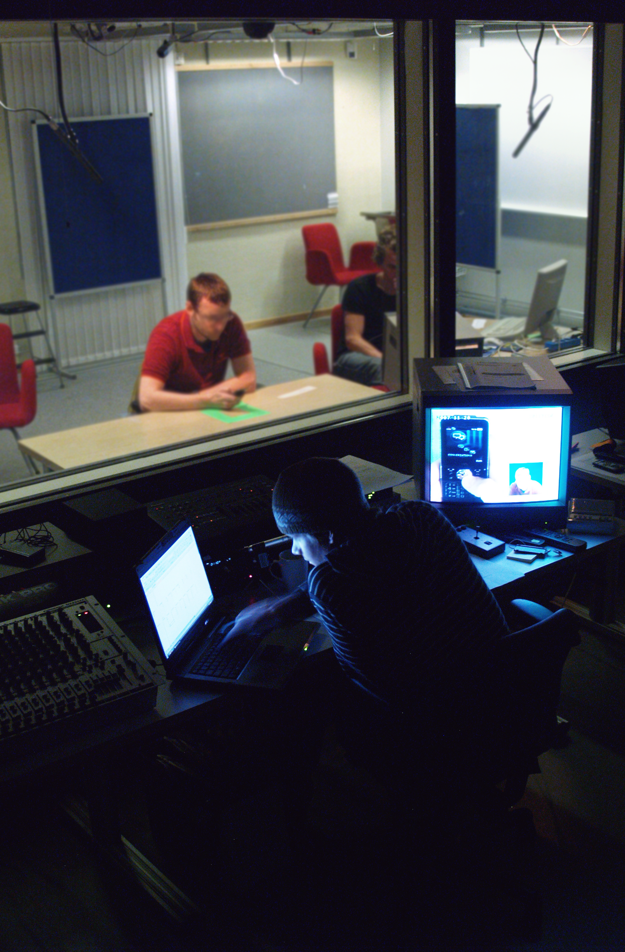 two people on either side of a one-way mirror, seen from the observation room. Photo.