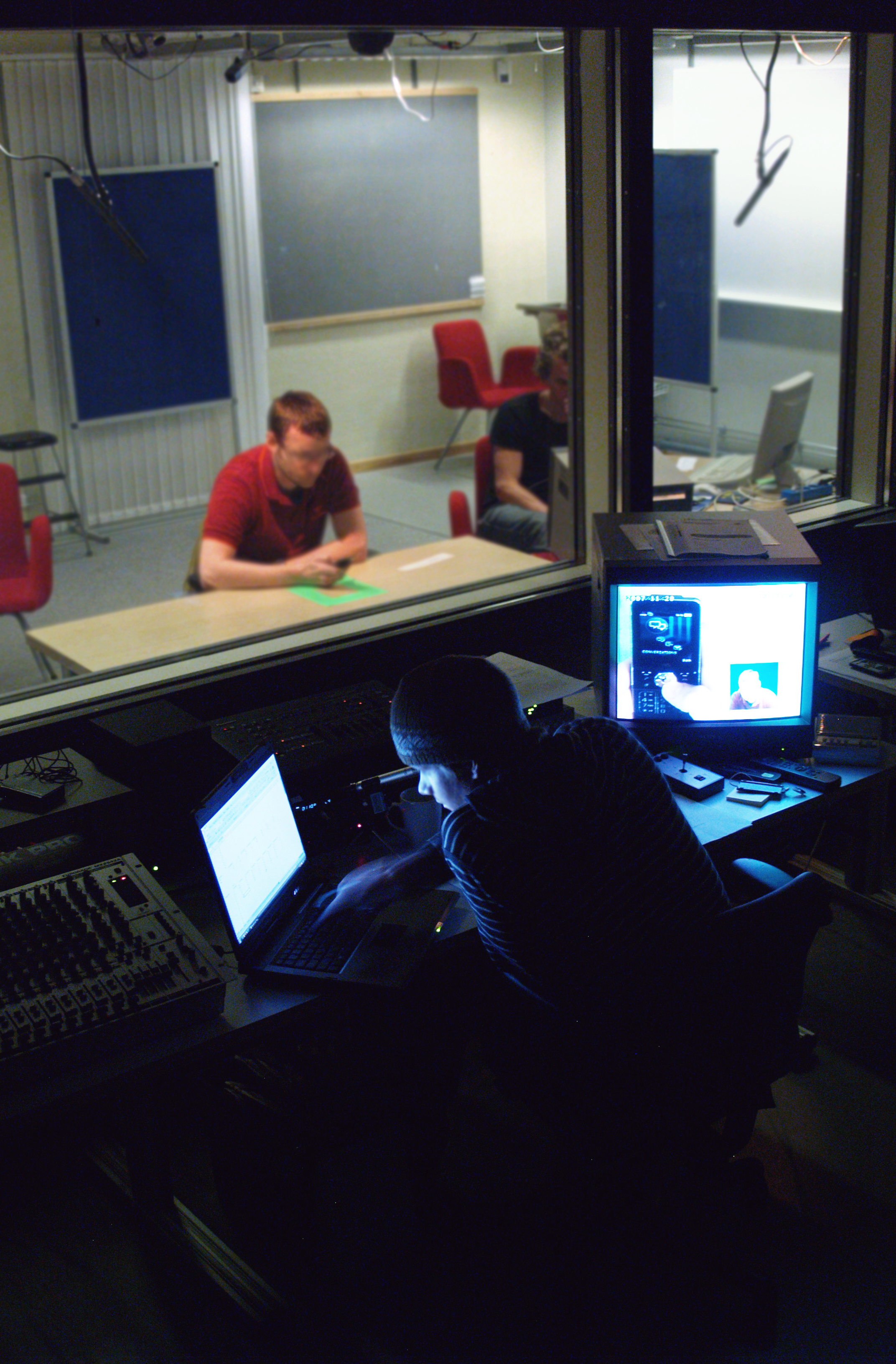 two people on either side of a one-way mirror, seen from the observation room. Photo. 