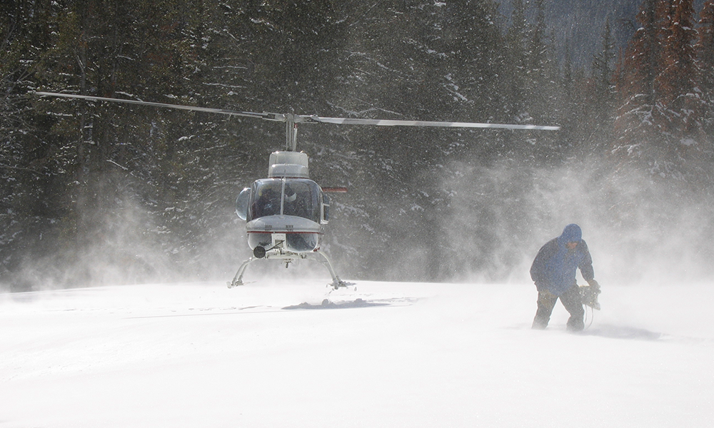 A person and a helicopter in a snowy landscape. Photo.