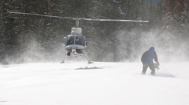 Person och helikkopter i vinterlandskap och snöyra. Foto.